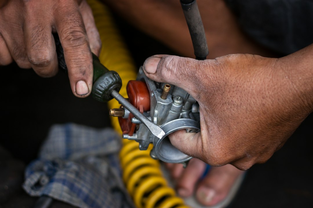 Mechanic's hands repairing a carburetor with a screwdriver