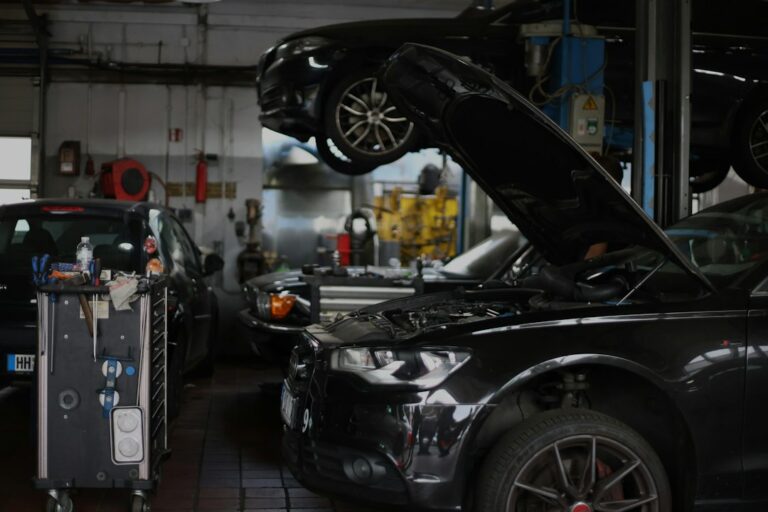 Black cars in a busy auto repair shop with tools on a rolling cart